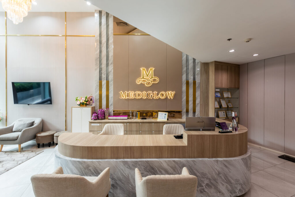 ภาพบรรยากาศเคาน์เตอร์ต้อนรับดีไซน์หรูหราหินอ่อนผสมงานไม้ของ MEDIGLOW Clinic สาขาทองหล่อ ณ ชั้น 1 อาคารเมเจอร์ ทาวเวอร์